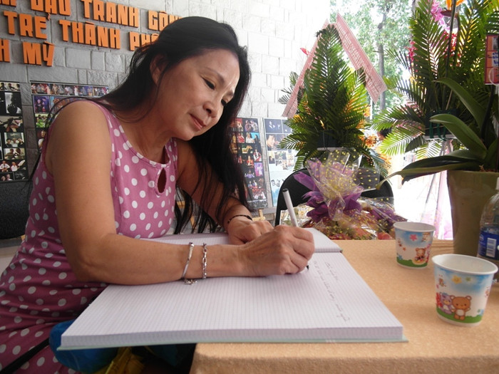 NSƯT Kim Xuân đang viết cảm nghĩ về buổi triển lãm. Chị là 1 trong 300 nhân vật tiêu biểu của ống kính Nguyễn Á.