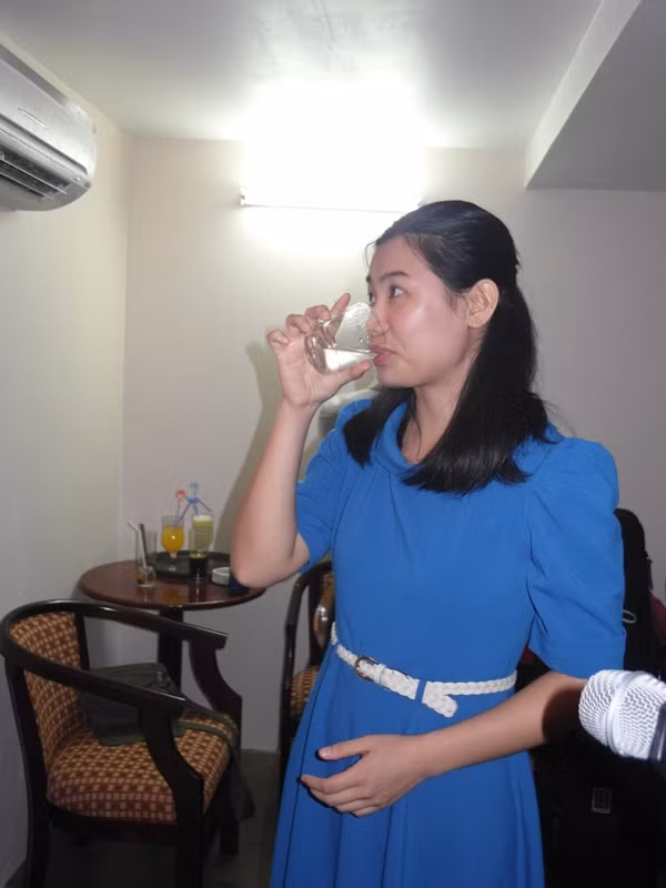 Hương Thảo tranh thủ uống nước, lấy giọng trước giờ biểu diễn.