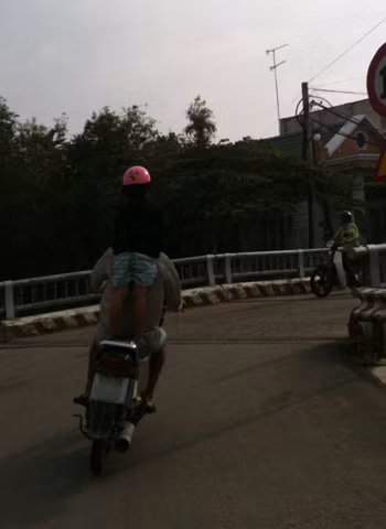 "Trẻ em làm xiếc cùng ba": Em bé một tay giữ mũ, còn một tay bám lấy ba trên xe máy. Chụp tại thị trấn Lái Thiêu, Thuận An, Bình Dương. Ảnh: Trịnh Văn Hải. "Trẻ em làm xiếc cùng ba": Em bé một tay giữ mũ, còn một tay bám lấy ba trên xe máy. Chụp tại thị trấn Lái Thiêu, Thuận An, Bình Dương. Ảnh: Trịnh Văn Hải.