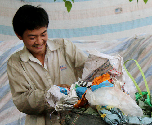 Người đàn ông này để vợ con lại vùng quê Thanh Hóa ra đây làm thuê cho một chủ vựa ve chai. Công việc chính của anh là giũ túi nilon cho hết rác rồi đóng vào bì, mỗi kg bán được 5.000 đồng.
