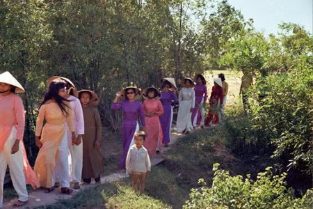 Cô dâu là người mặc áo hồng, đi giữa hai phụ nữ mặc áo dài tím.