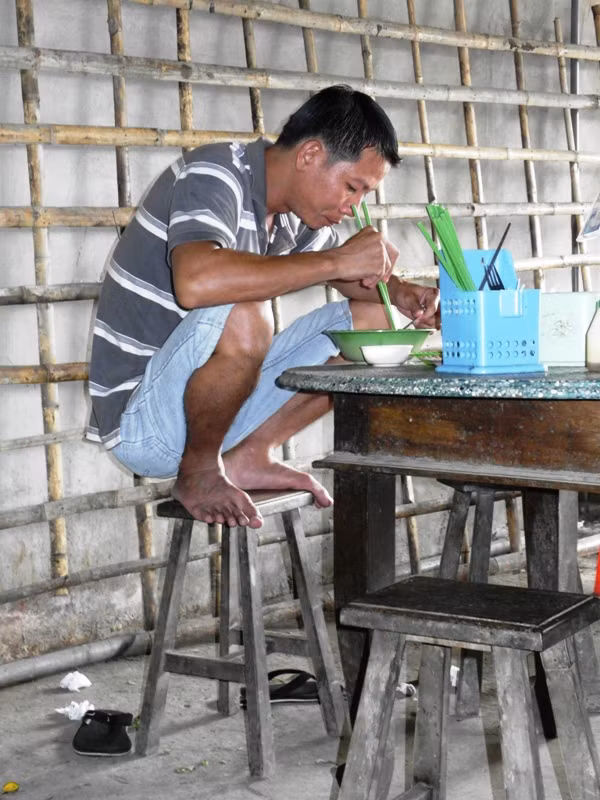 Anh thanh niên này ngồi thưởng thức món chào đúng kiểu "nước lụt" của người miền Tây. Ngày trước, mỗi khi nước tràn về ruộng, vườn, ngập lênh láng nhà, ngồi ăn cơm, người miền Tây thường rút chân lên ghế, ngồi chồm hổm để tránh nước. Bây giờ, ở miền Tây, nếu thấy ai ngồi thế này, sẽ bị gọi là "ngồi kiểu nước lụt".