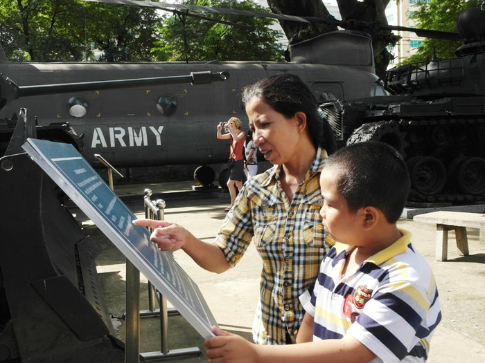 Một nơi thu hút khách tham quan trong ngày Quốc khảnh khác tại TP.HCM: Bảo tàng chiến tích chiến tranh. Sáng nay, chị Phạm Thị Thương đã dẫn con trai là Phạm Đông Dương đến địa điểm lưu giữ nhiều hiện vật trong thời chiến này Trong ảnh:. Chị Thương đang đọc cho con trai nghe những dòng chú thích cách sử dụng của một loại xe tăng.