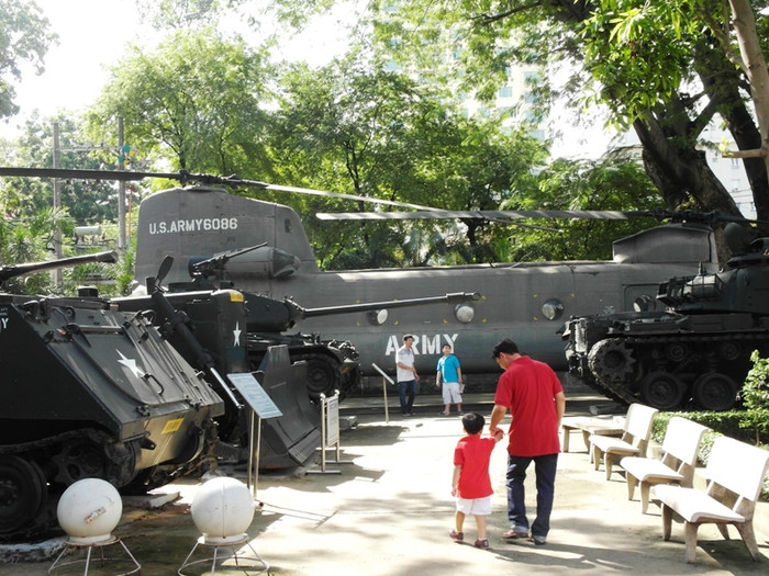 Một cháu bé nắm tay cha, lẫm chẫm bước đi xem những vũ khí của một thời lửa đạn nay im lặng trong góc bảo tàng rợp bóng cây