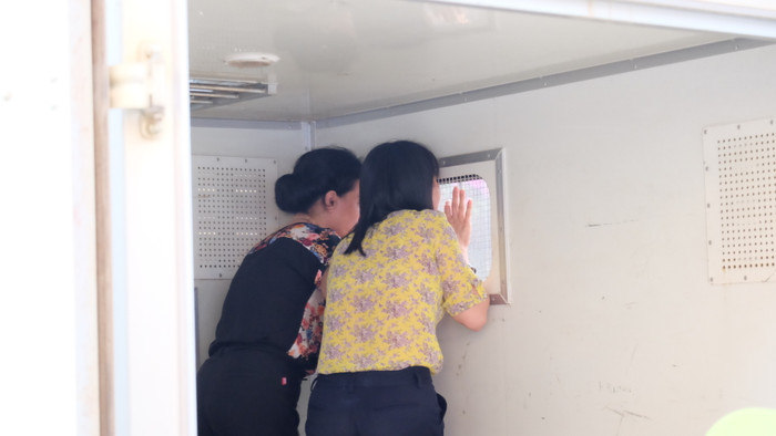 Hai bị cáo Liên và Loan gọi người thân sau cánh xe tù. Hai bị cáo Liên và Loan gọi người thân sau cánh xe tù.