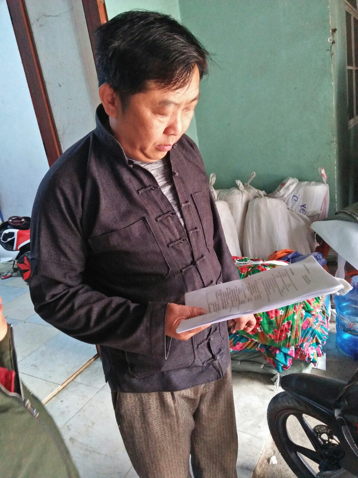 Một phụ huynh ở Phố Cáo cầm bài ôn của các con em. Một phụ huynh ở Phố Cáo cầm bài ôn của các con em.