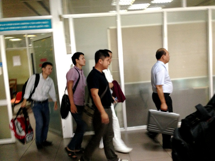 Ông Khai trong vòng vây của lực lượng an ninh, mặc thường phục.