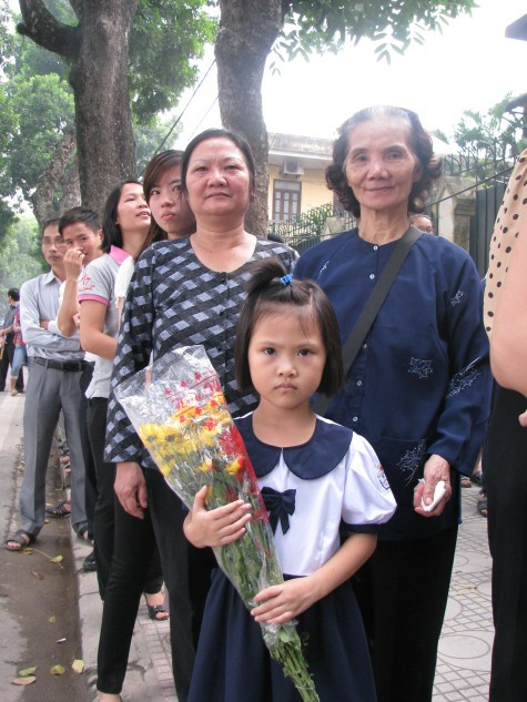 Em nhỏ đứng trên tay mang bó hoa cũng xếp hàng chờ đến lượt.