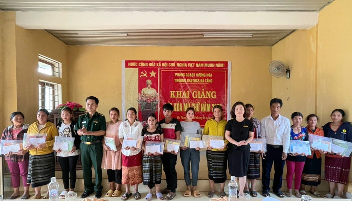 Cô giáo Phạm Thanh Nga - Trưởng phòng Giáo dục và Đào tạo Hướng Hóa (thứ 6 từ phải qua) cùng Thiếu tá Hồ Văn Hai, Đội trưởng kiểm soát hành chính, Đồn Biên phòng Ba Tầng và lãnh đạo địa phương trao đồ dùng học tập cho các học viên lớp xóa mù. Ảnh: Ngọc Hiển