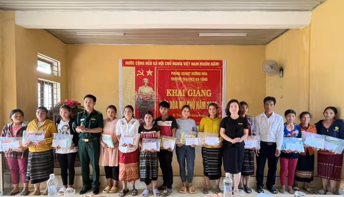 Cô giáo Phạm Thanh Nga - Trưởng phòng Giáo dục và Đào tạo Hướng Hóa (thứ 6 từ phải qua) cùng Thiếu tá Hồ Văn Hai, Đội trưởng kiểm soát hành chính, Đồn Biên phòng Ba Tầng và lãnh đạo địa phương trao đồ dùng học tập cho các học viên lớp xóa mù. Ảnh: Ngọc Hiển