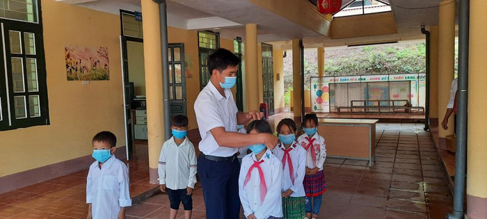 Các thầy cô chăm sóc, hướng dẫn đeo khẩu trang trước khi vào lễ khai giảng.