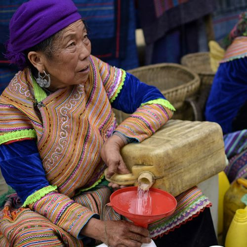 Một người phụ nữ dân tộc thiểu số khác đang bán rượu trắng ở chợ Bắc Hà.