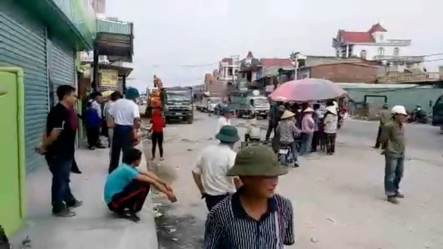 Người dân kê ghế, dựng ô ngay dưới lòng đường yêu cầu nhà thầu phải bồi thường xong mới thi công (ảnh cắt từ clip)