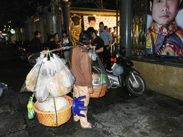 Một bà lão gánh hàng rong, dừng chân bên đường, tần ngần nhìn vào quang cảnh náo nhiệt của tiệc sinh nhật. Một bà lão gánh hàng rong, dừng chân bên đường, tần ngần nhìn vào quang cảnh náo nhiệt của tiệc sinh nhật.