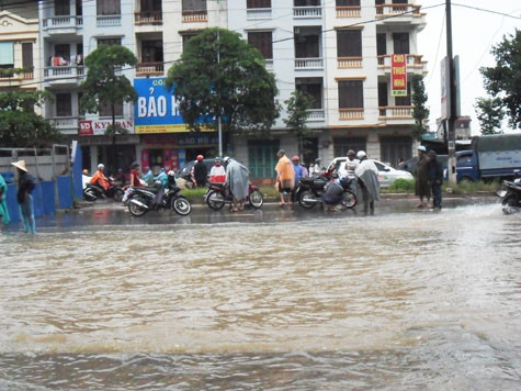 Cũng gặp tình trạng xe bị chết máy như cô Yên, chị Thu (Chúc Sơn) cho biết: đường ngập quá xe không thể đi nổi, đi được một đoạn đã bị chết máy, tôi cũng đem vào cho người ta sửa, chỉ dốc hết nước ở bô ra là lại đi ngon. (Ảnh: . Đường bị ngập sâu, nhiều phương tiện lưu thông bị chết máy.)