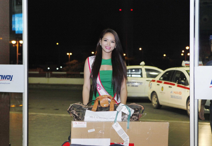 Trong chiếc áo dạ hội màu xanh nõn chuối, băng đeo danh hiệu "Hoa khôi", Hương Thảo đẩy hành lý vào phòng check in.