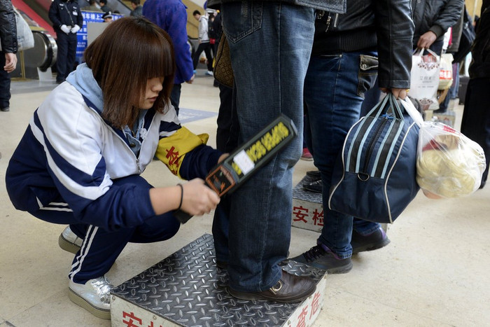 Một nữ sinh dùng thiết bị kiểm tra an ninh đối với hành khách chuẩn bị lên tàu Một nữ sinh dùng thiết bị kiểm tra an ninh đối với hành khách chuẩn bị lên tàu