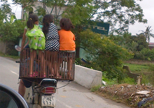 Ba đứa bé vắt vẻo trên chiếc lồng sau yên xe, chụp tại quốc lộ 45. Ảnh: Người Quê. Ba đứa bé vắt vẻo trên chiếc lồng sau yên xe, chụp tại quốc lộ 45. Ảnh: Người Quê.