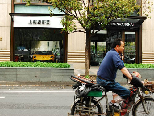 Một người lao động đi ngang qua salon bán xe sang. Một người lao động đi ngang qua salon bán xe sang.