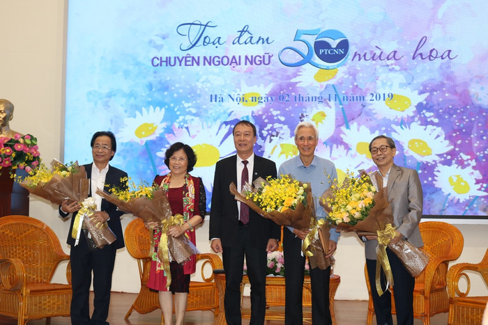 Phó Giáo sư, Tiến sĩ Nguyễn Thành Văn tặng hoa cho các thầy, cô nguyên là lãnh đạo, giáo viên, cựu học sinh của trường tại tọa đàm Phổ thông Chuyên Ngoại ngữ - 50 mùa hoa. Ảnh: Đỗ Thơm