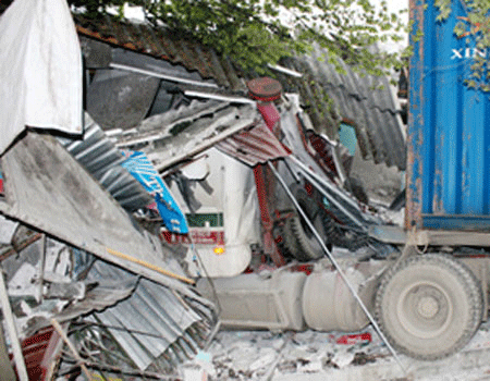 Lúc 1g20 sáng ngày 15.2.2012, một vụ tai nạn nghiêm trọng xảy ra trên QL5 thuộc địa phận xã Tuấn Hưng, huyện Kim Thành, tỉnh Hải Dương. Vào thời điểm trên, chiếc container BKS:16H-6832 kéo rơ-mooc BKS:16R-0225 mang hiệu VinaShin lưu thông theo hướng Hải Dương - Hải Phòng, đến khu vực ga Phạm Xá, xã Tuấn Hưng thì bất ngờ lao vào nhà dân. Cú húc quá mạnh đã làm sập cửa hàng bán giày dép của gia đình anh Tiêu Văn Tùng, và quán nước giải khát của chị Trần Thị Nhung. Ảnh: Phần đầu xe lọt thỏm trong đống đổ nát (Pháp luật và Xã hội).