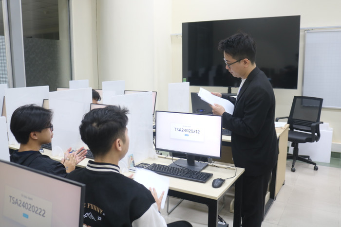 Giám thị phát giấy nháp cho thí sinh. Ảnh: Doãn Nhàn