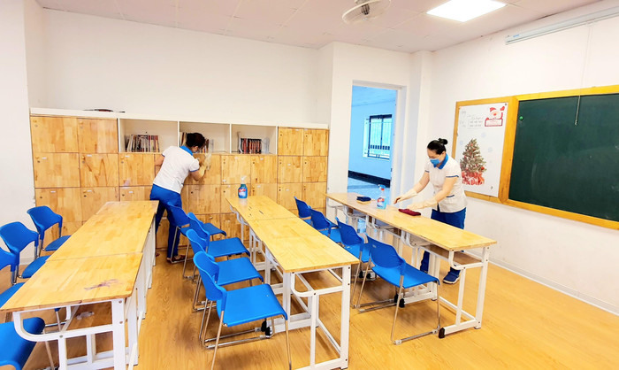 Bàn ghế, các tủ trong lớp học được nhân viên của trường lau chùi, sát khuẩn. Ảnh: NTCC