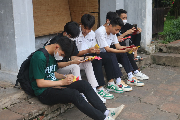 Từng tốp học sinh ngồi ghi thông tin cá nhân, ngày thi, phòng thi, nguyện vọng vào sớ trước khi làm lễ
