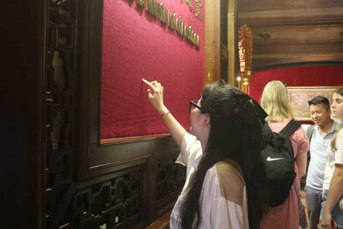 Một số bạn dùng ngón tay viết nhẹ lên lớp vải nhung, nơi có dòng chữ "Hiền tài là nguyên khí quốc gia để mong xin được sự may mắn