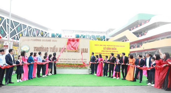 Các đại biểu thực hiện nghi lễ gắn biển công trình Trường Tiểu học Hoàng Mai