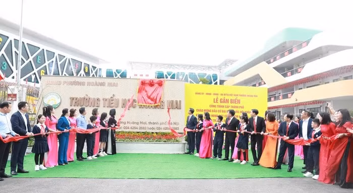 Các đại biểu thực hiện nghi lễ gắn biển công trình Trường Tiểu học Hoàng Mai