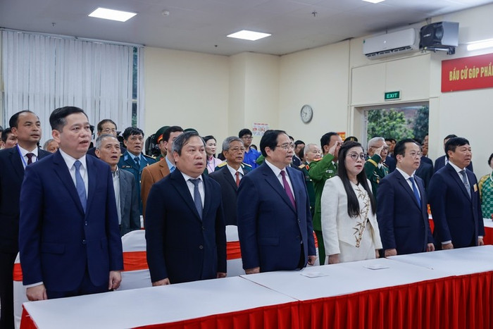 Thủ tướng Chính phủ Phạm Minh Chính và Phu nhân cùng các đại biểu thực hiện nghi lễ chào cờ trước khi bỏ phiếu. Ảnh: baochinhphu.vn.