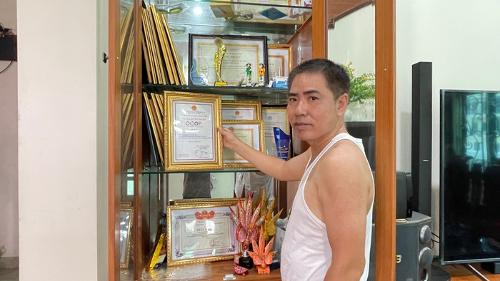 Ông Nguyễn Văn Tái bên cạnh tủ trưng bày giấy khen và kỷ niệm chương vì những cống hiến cho sản phẩm chuồn chuồn tre Thạch Xá. Ông không khỏi đau đáu và lo lắng vì sản phẩm của làng nghề đang có nguy cơ bị mai một. z6869340213967-3dd5b09d2f76665967dd6e6fe06eeed0.jpg