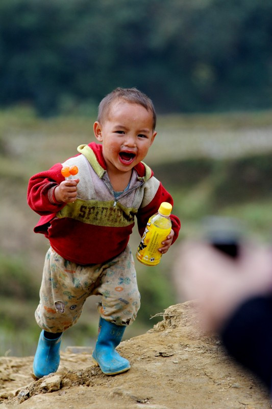 Một cậu bé kháu khỉnh chạy nhanh tới chỗ du khách để xin kẹo, mặc dù trên tay em đã hết chỗ cầm. Một cậu bé kháu khỉnh chạy nhanh tới chỗ du khách để xin kẹo, mặc dù trên tay em đã hết chỗ cầm.