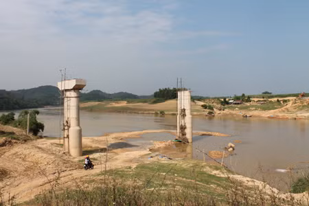 Những chiếc cầu có chiều dài khoảng 30m đang thi công dở. Tại cây cầu Phú Sơn, những nhịp cầu đang thi công nay bị bỏ lại dang dở. Những chiếc máy nằm im, không còn thấy công nhân nào làm việc ở đây. Hàng ngày, người dân muốn qua cầu đều phải trả tiền đò. Người dân ở đây đều mong muốn những chiếc cầu này được hoàn thành để đảm bảo an toàn mỗi khi qua sông. Tuy nhiên, chúng vẫn cứ bất động như thế! ( Ảnh: một cây cầu đang xây dựng dở bị bỏ lại).