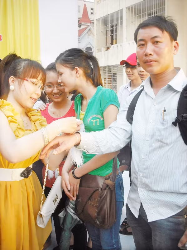 Cô gái Lào xinh đẹp cột chỉ chúc phúc cho cánh phóng viên tác nghiệp trong buổi lễ
