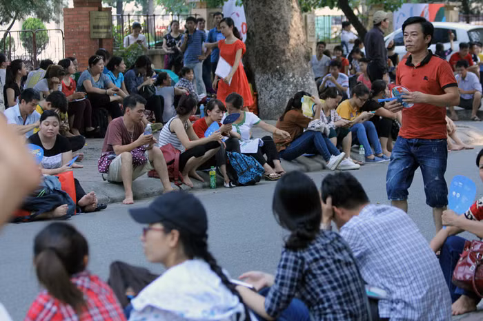 Bên ngoài, dưới trời nắng nóng rất nhiều phụ huynh và người nhà thí sinh đứng, ngồi chờ mướt mồ hôi.