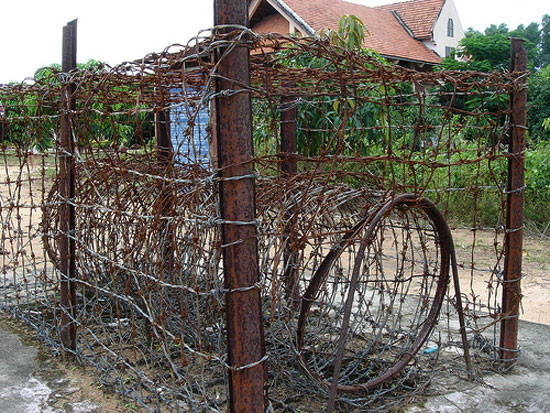 Chuồng cọp kẽm gai tra tấn người tù được làm ngoài trời trên nền cát. Tù nhân bị nhốt vào đây sau khi bị lột bỏ quần áo, và bị bỏ đói vài ngày liền Chuồng cọp kẽm gai tra tấn người tù được làm ngoài trời trên nền cát. Tù nhân bị nhốt vào đây sau khi bị lột bỏ quần áo, và bị bỏ đói vài ngày liền