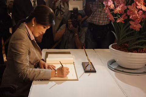 Thủ tướng Thái Lan Yingluck Shinawatra viết vào sổ lưu niệm trong buổi lễ công bố loài hoa phong lan mang tên bà tại Vườn Sinh học Singapore hôm 9/12. Ảnh: The Wall Street Journal. Thủ tướng Thái Lan Yingluck Shinawatra viết vào sổ lưu niệm trong buổi lễ công bố loài hoa phong lan mang tên bà tại Vườn Sinh học Singapore hôm 9/12. Ảnh: The Wall Street Journal.