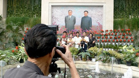 Người dân chụp ảnh với hoa "Kim Nhật Thành" và hoa "Kim Chính Nhật", phía sau là chân dung của hai vị lãnh đạo đất nước. Ảnh: CNNGo