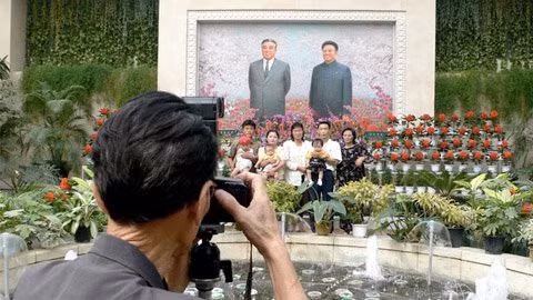 Người dân chụp ảnh với hoa "Kim Nhật Thành" và hoa "Kim Chính Nhật", phía sau là chân dung của hai vị lãnh đạo đất nước. Ảnh: CNNGo