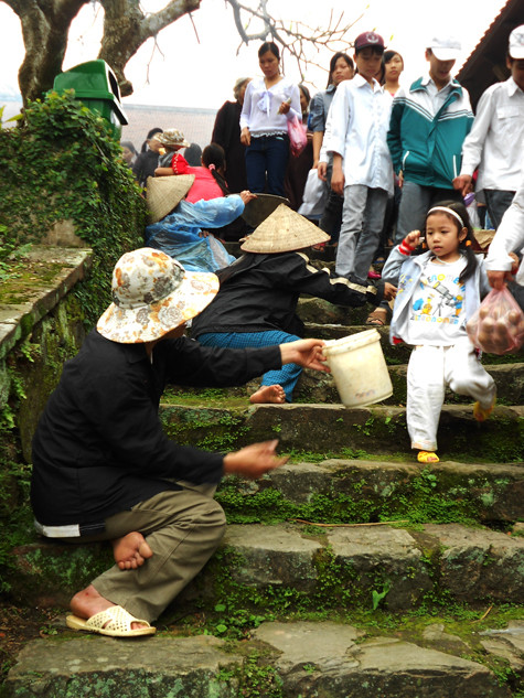 Dọc theo lối lên chùa là đội ngũ "cái bang" đứng, nằm ngả ngớn với đủ kiểu chiêu trò để xin tiền du khách.