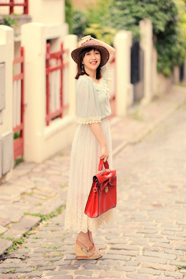 Lan Chi Vũ thướt tha và dịu dàng với váy xếp ly ren cùng điểm nhấn là túi satchel màu đỏ rực.