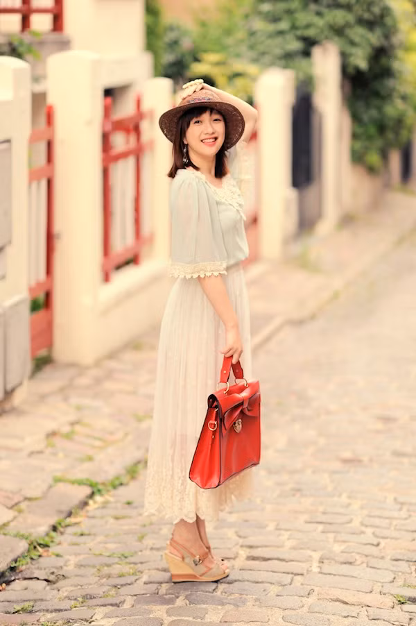 Lan Chi Vũ thướt tha và dịu dàng với váy xếp ly ren cùng điểm nhấn là túi satchel màu đỏ rực.