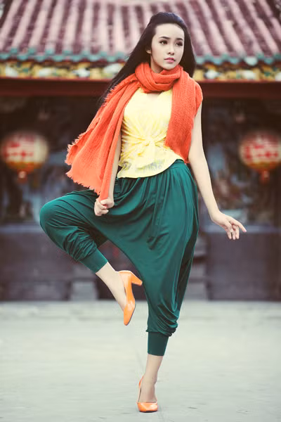 Quần alibaba màu xanh ve free-size may thụng phần hông tạo những vết xếp hai bên thân kết hợp áo thun ngắn tay màu vàng chanh khiến Bảo Trân trông thật trẻ trung và năng động. Khăn choàng cổ chất liệu sợi cotton dệt màu cam tạo điểm nhấn mùa thu ấn tượng.