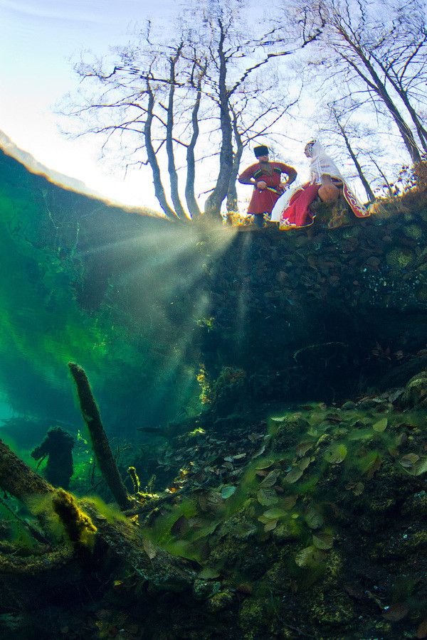 Đôi nam nữ trong trang phục truyền thống của người Balkar - một dân tộc thiểu số ở nước Nga đang đứng bên rìa hồ. Bức ảnh được chụp từ dưới mặt nước. Đôi nam nữ trong trang phục truyền thống của người Balkar - một dân tộc thiểu số ở nước Nga đang đứng bên rìa hồ. Bức ảnh được chụp từ dưới mặt nước.