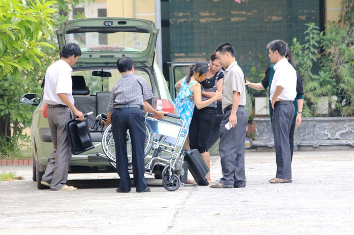 Cô bé được chuyển lên phòng thi bằng xe lăn của gia đình.