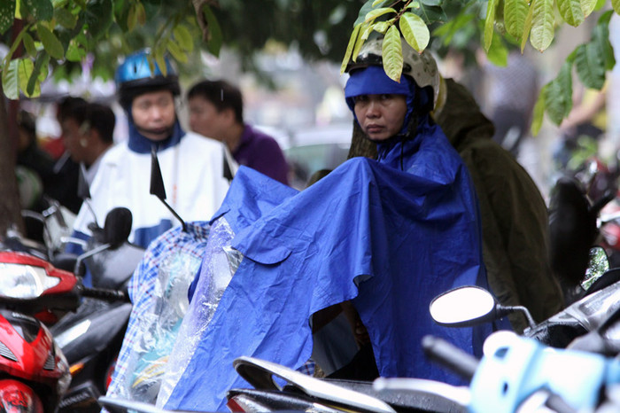 Gần tới giờ làm bài cũng là lúc cơn mưa rào bất chợt đổ xuống, kiên nhẫn mặc áo mưa chờ con.