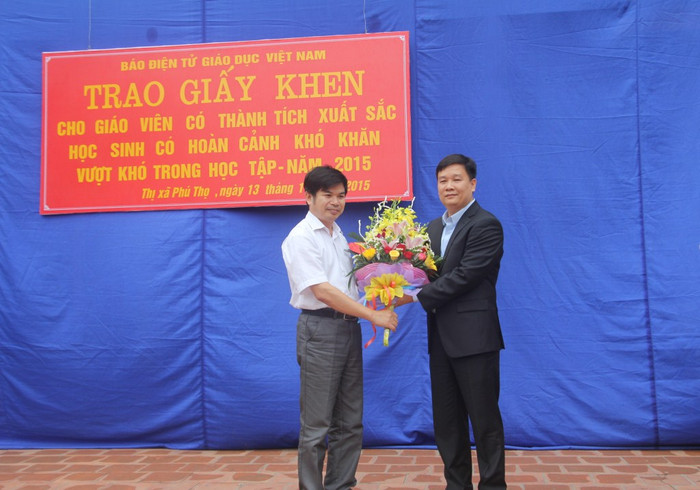 Ông Nguyễn Tân Sơn (trái) - Trưởng Phòng Giáo dục và Đào tạo thị xã Phú Thọ tặng hoa cho ông Nguyễn Tiến Bình, Tổng biên tập Báo điện tử Giáo dục Việt Nam.