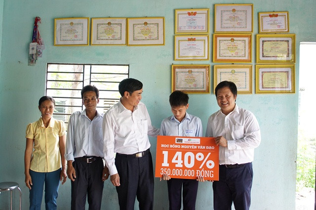 Giám đốc Sở GD&amp;DT Đà Nẵng (thứ 3 bên phải) và Hiệu trưởng Trường ĐH FPT (đầu tiên bên phải) trao học bổng cho Nguyễn Ngọc Dưỡng và gia đình. Ảnh Vân Anh